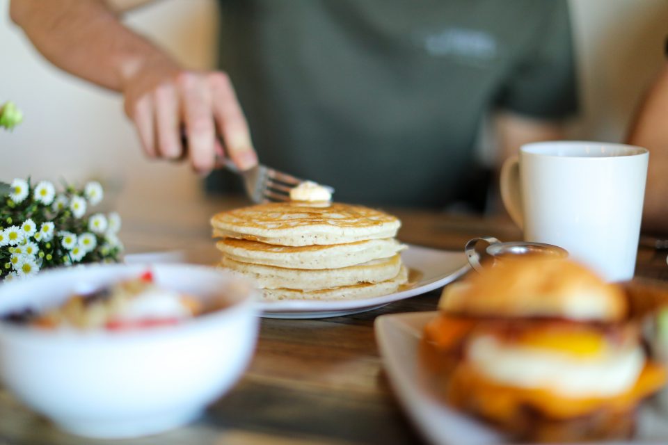 a fork cuts through a stack of pancakes that lie on a plate