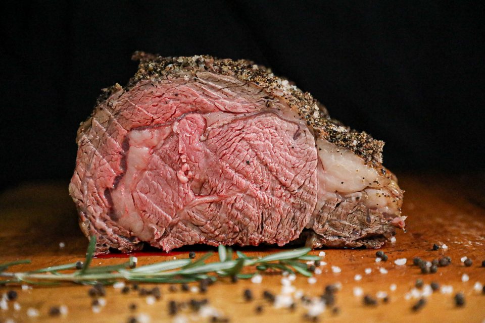 prime rib roast sits on a cutting board with salt and pepper sprinkled in front